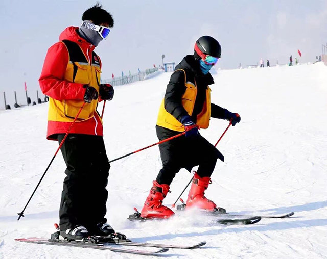 游客在雪场体验滑雪的快乐。